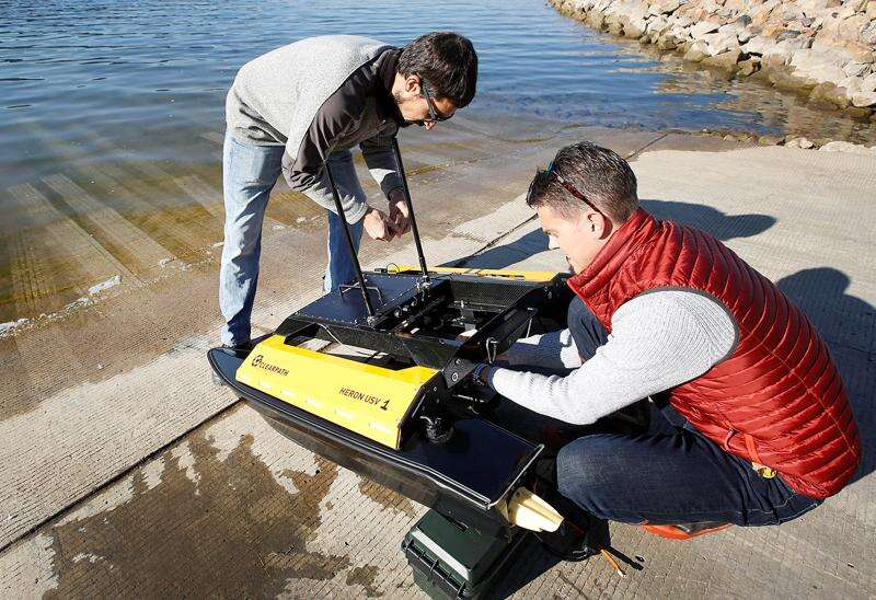 Ryan Smith and Jordan Brenner preparing an autonomous aquatic vehicle for environmental monitoring work